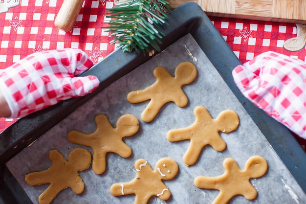 Raw gingerbread men with glaze on a baking sheet