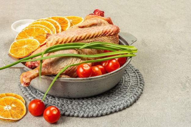 Raw goose with vegetables and spices. Traditional ingredient for preparing festive and healthy food, rustic style. Light stone concrete background, copy space