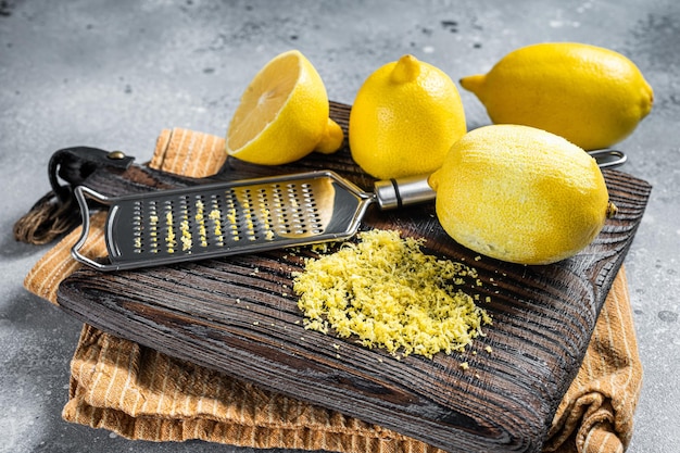 Foto scorza di limone grattugiata cruda su tavola di legno. sfondo grigio. vista dall'alto.