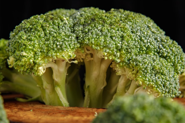 Foto fiori di broccoli verdi crudi su una tavola di legno con gli ingredienti in primo piano