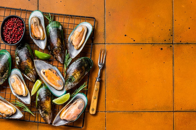 Raw green kiwi mussels in shells with herbs Orange background Top view Copy space