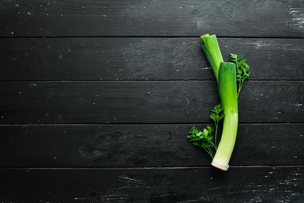 黒の背景に生の緑のネギ健康的な食事のための野菜トップビュー無料コピースペース