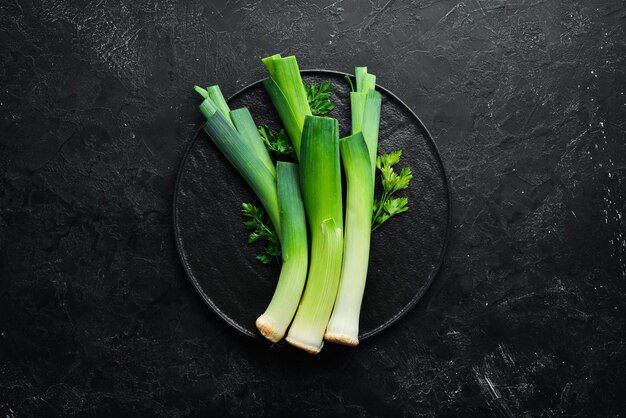 黒の背景に生の緑のネギ健康的な食事のための野菜トップビュー無料コピースペース