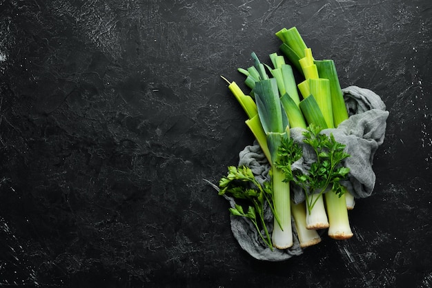 黒の背景に生の緑のネギ健康的な食事のための野菜トップビュー無料コピースペース