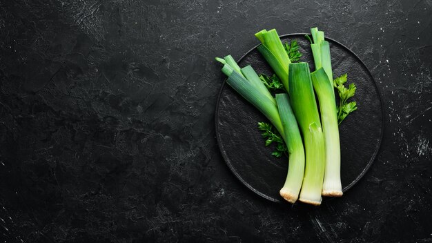 Сырой зеленый лук-порей на черном фоне Овощи для здорового питания Вид сверху Бесплатное пространство для копирования