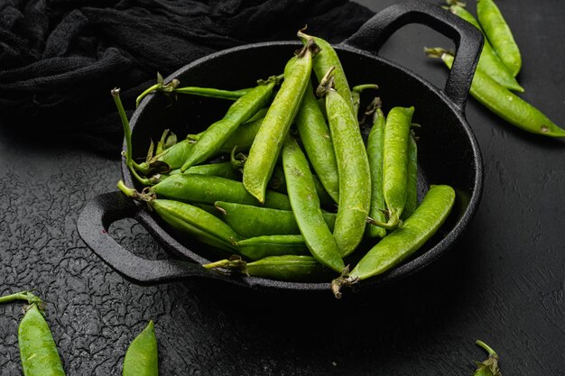 Raw Green Organic Snow Peas on black dark stone table background