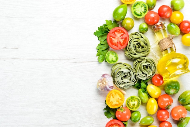 写真 白い木製の背景にトマトオイルとパセリと生の緑のパスタイタリアの伝統的な料理新鮮な野菜トップビューあなたのテキストのための自由なスペース