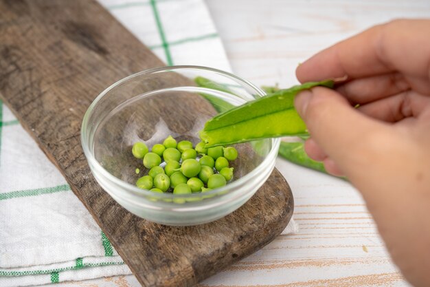 Raw green pea in a glass bowl on wooden board