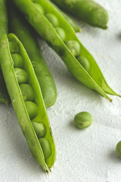 Raw green pea pods on light background