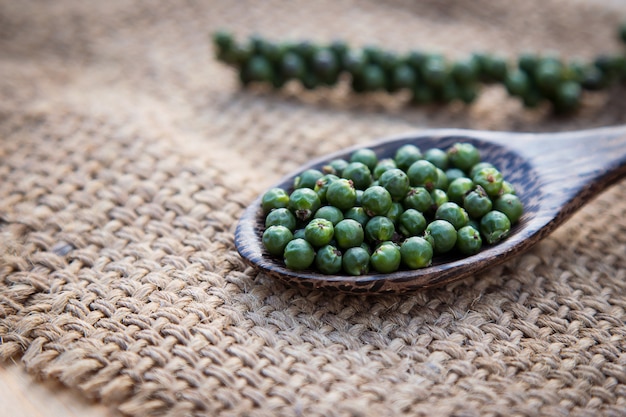 raw green pepper on wooden spoon 