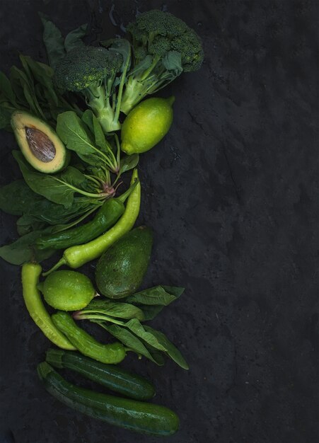 Raw green vegetables set. broccoli, avocado, pepper, spinach, zuccini, lime on  dark stone