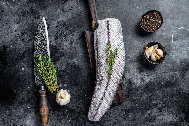 Raw grenadier macrurus white fish on a wooden cutting board.  Top view.