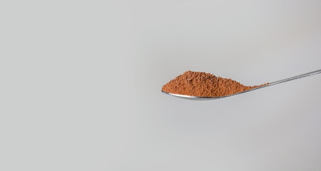 Raw of grinding cocoa or coffee on tea spoon for making drinking cup or bakery with black background