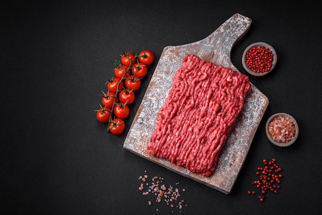 Raw ground beef or pork on a wooden cutting board with spices and salt