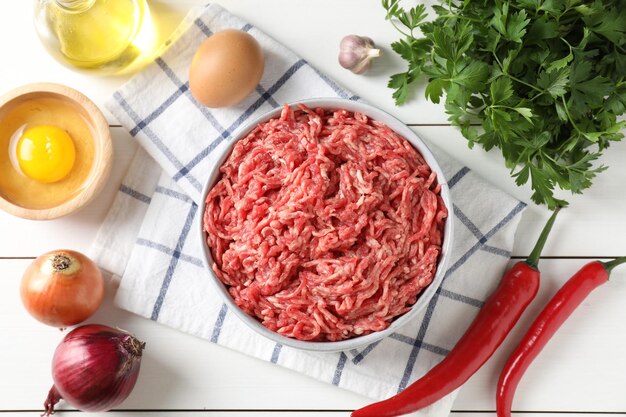 白い木製のテーブルに平らに置かれた鉢の中の生地肉と様々な製品