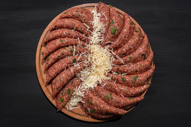 Raw ground meat cutlets on a chopping board. raw mince on black\
isolated background. top view