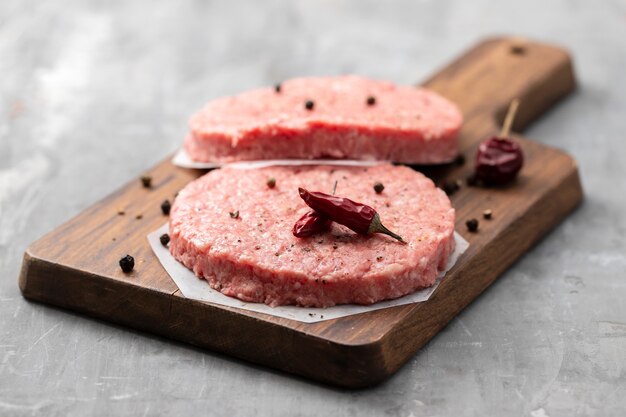 Raw ground meat with black pepper on wooden board