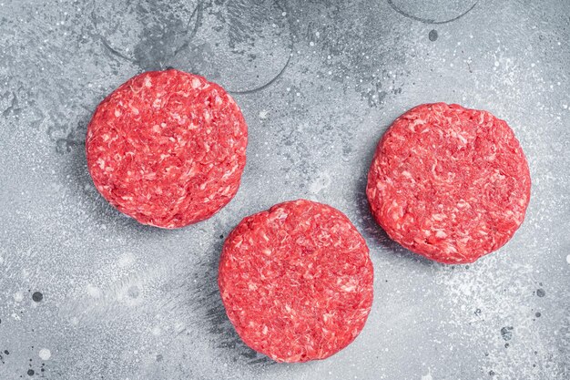 Raw Ground mince beef meat Burger steak cutlets. Gray background. Top view.