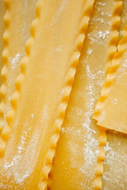 Raw hard homemade fluted lasagna sheets in flour close-up real life atmosphere homemade pasta made