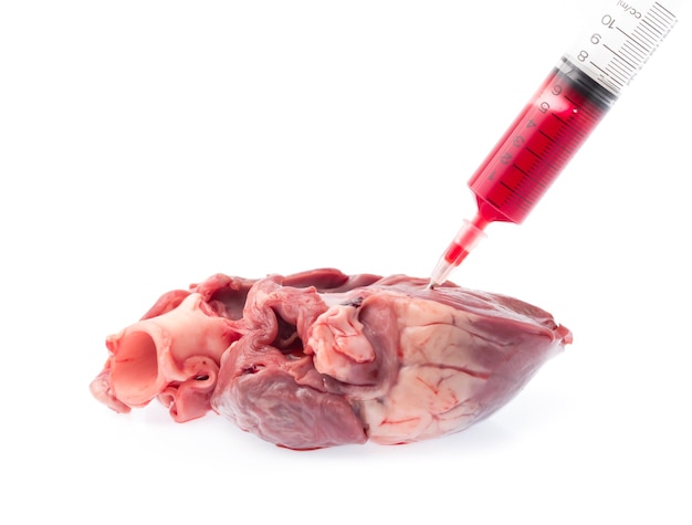 Photo raw heart with blood syringe for injection isolated on white background