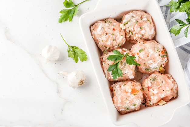 Raw homemade chicken or turkey meatballs in baking dish