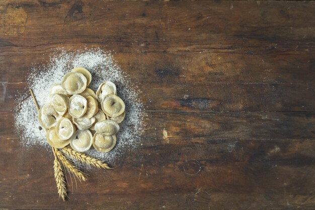 Фото Сырые домашние вкусные традиционные итальянские пельмени равиоли с мясом на темной деревянной старой поверхности, вид сверху, копия пространства