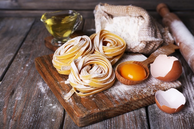 Raw homemade pasta and ingredients for pasta on wooden background