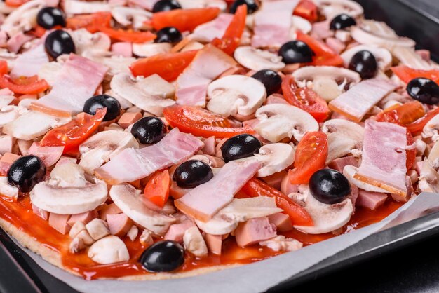 Raw homemade pizza and ingredients on black concrete table top view