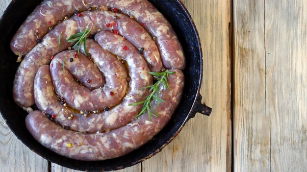 Raw homemade sausages with spices in a pan