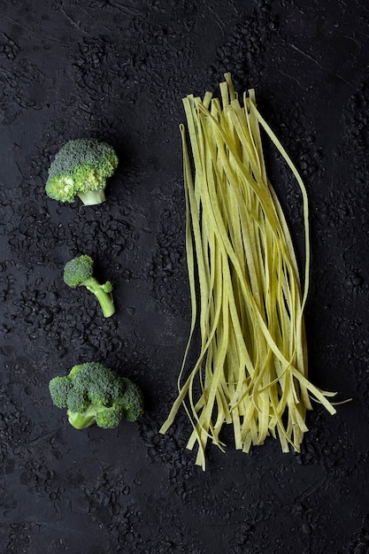 Raw homemade tagliatelle with broccoli on black