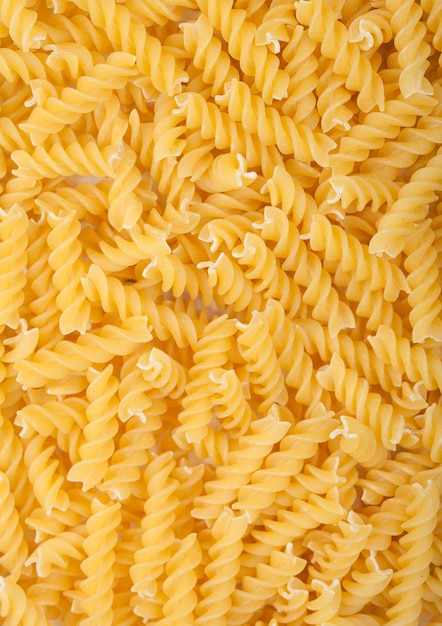 Raw homemade yellow fusilli pasta as texture background. Top view