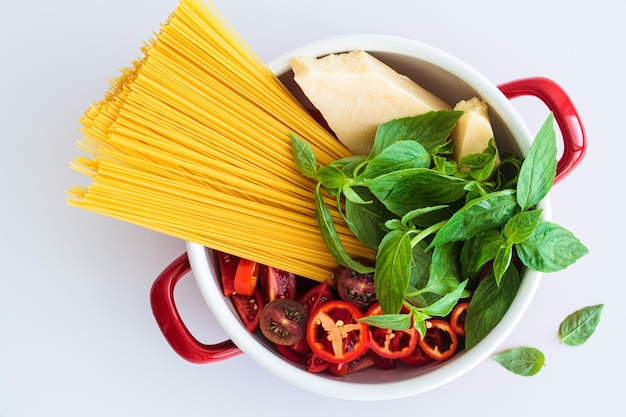 Photo raw ingredients for pasta spaghetti parmesan vegetables and basil in saucepan