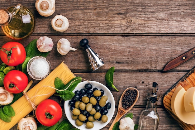 Raw ingredients for the preparation of italian pasta spaghetti basil tomatoes olives and olive oil o