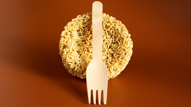 Foto tagliatelle istantanee crude a forma di cerchio con una forchetta usa e getta in legno. pasta, per la cui preparazione è sufficiente versare acqua bollente e attendere qualche minuto. spaghetti. copia spazio.