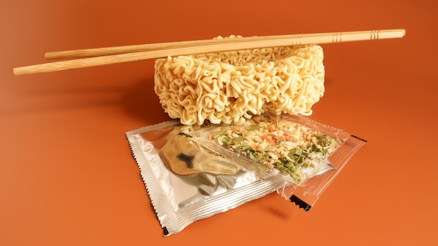 Raw instant noodles with chopsticks and spices. Copy space asian food. pasta, for the preparation of which it is enough to pour boiling water and wait a few minutes. flavored spaghetti.