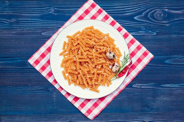 Raw italian pasta on dark blue wooden background, top view