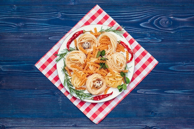 Pasta italiana cruda sulla tavola di legno blu scuro, vista superiore