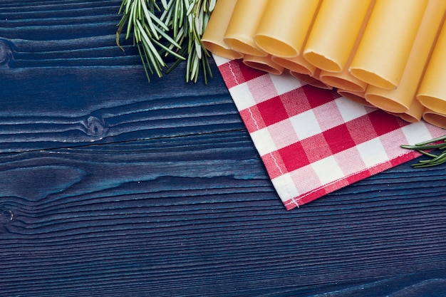Фото Сырые итальянские макароны на синем деревянном столе, вид сверху фон