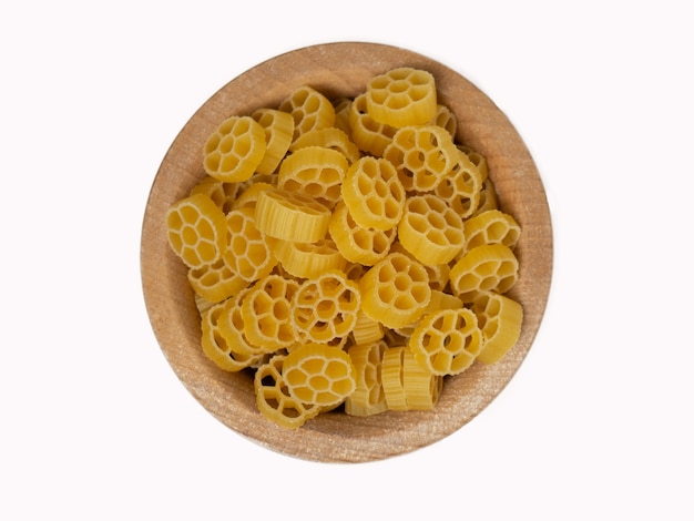 Сырые итальянские макароны в деревянной миске, изолированные на белом фоне, вид сверху