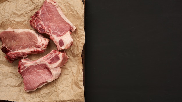 갈비뼈에 생 육즙이 많은 돼지 고기 조각, 음식은 갈색 양피지에 놓여 있습니다.