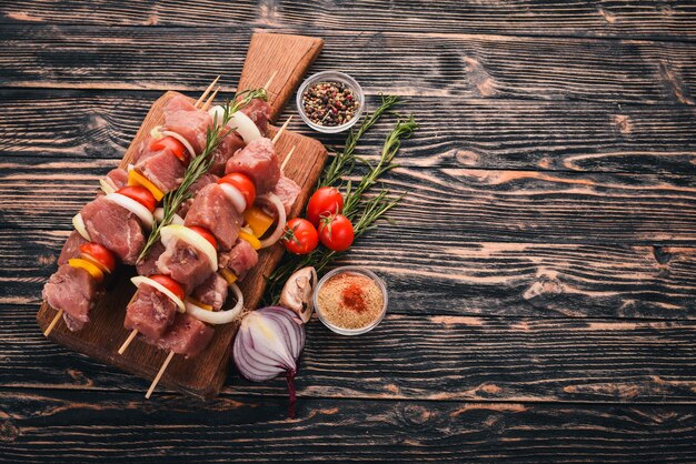 Raw kebab from meat on a wooden background with vegetables Top view Free space for text