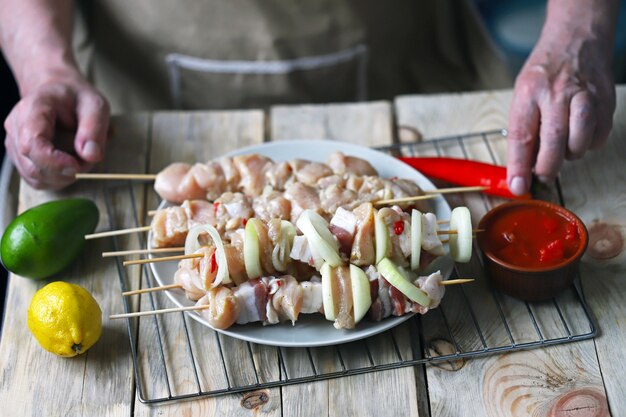 Raw kebabs on wooden sticks are prepared by the chef.