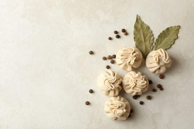 Raw khinkali, pepper and bay leaves on white textured