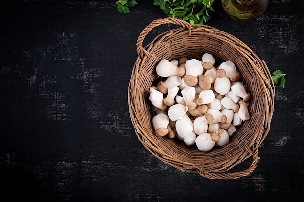 Raw king oyster mushrooms Pleurotus eryngii in basket on a dark background. Top view, above