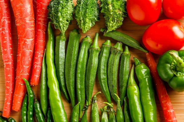 Raw ladyfinger and other vegetable on wooden board