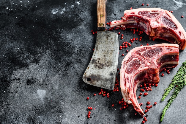 Raw lamb chops fresh cut with meat cleaver. Black background. Top view. Copy space