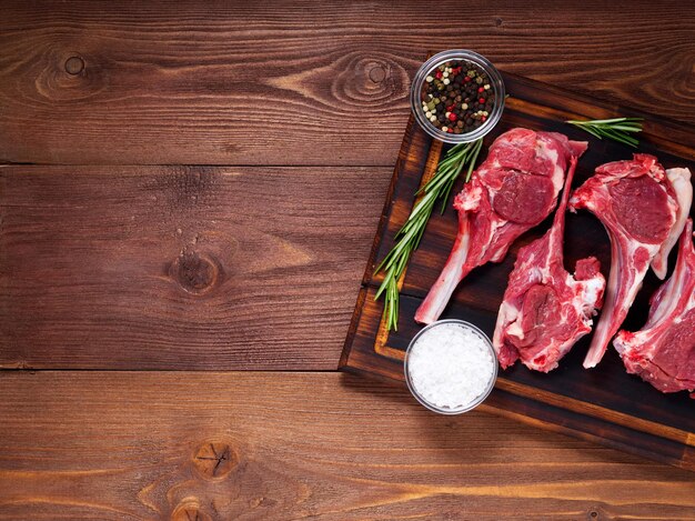 Raw lamb cutlets on bone on dark brown wooden background lamb ribs top view copy space