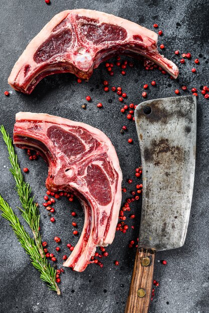 Raw lamb cutlets fresh cut with meat cleaver. Black background. Top view