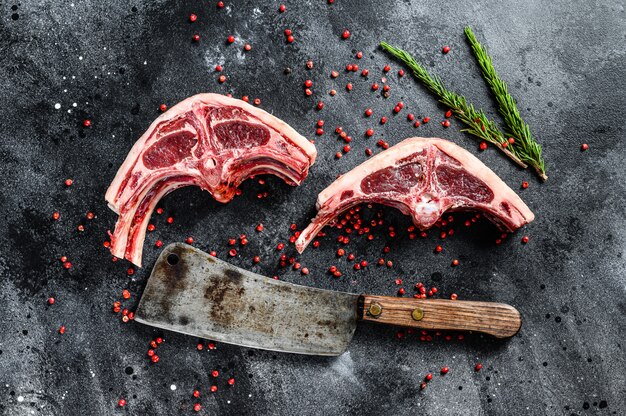 Raw lamb cutlets fresh cut with meat cleaver. Black background. Top view