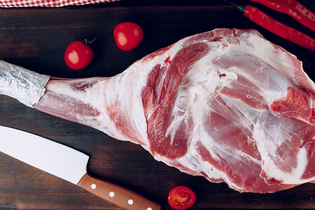 raw lamb leg on dark wooden board